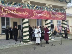 Panie prowadzące Garbowski jarmark Świąteczny na tle zabytkowego pałacu. Napis Garbowski Jarmark Świateczny.