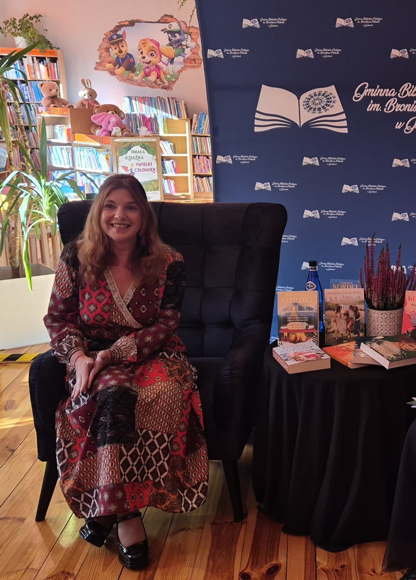 Magdalena Kordel siedząca w fotelu w bibliotece