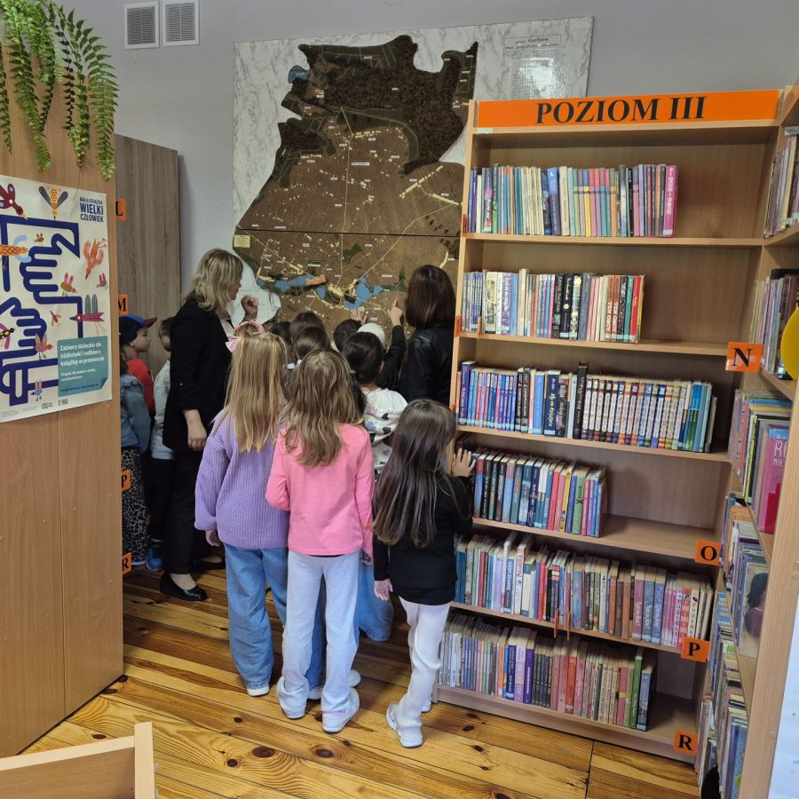 Dzieci ze Szkoły Podstawowej w Garbowie oglądające makietę Gminy garbów znajdującą się w bibliotece