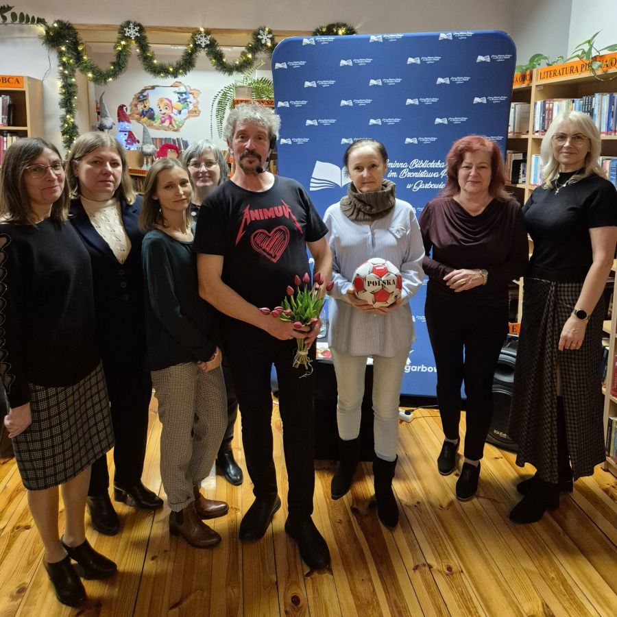 Piotr Pilarski z uczestniczkami spotkania autorskiego w bibliotece.