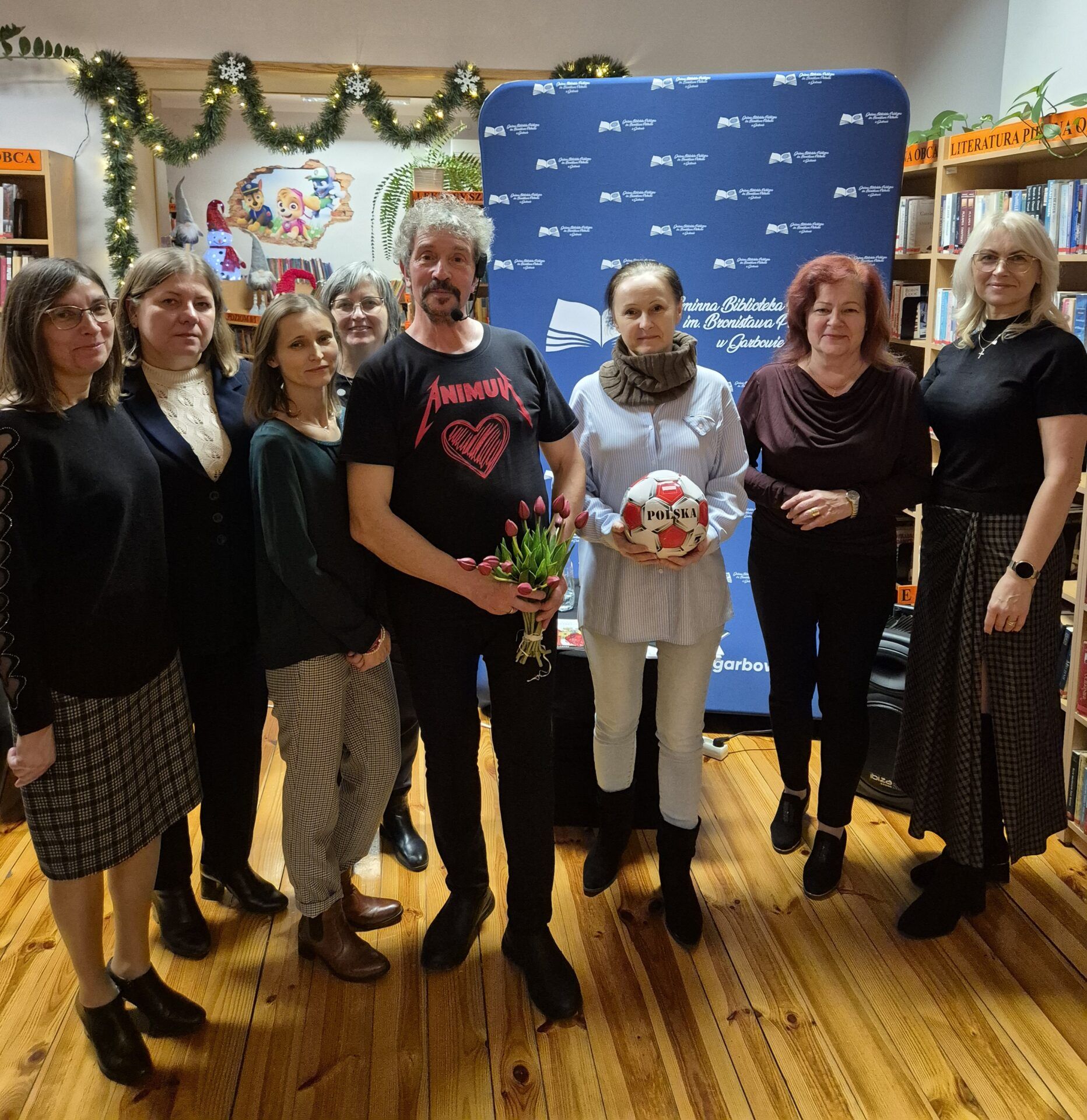 Piotr Pilarski z uczestniczkami spotkania autorskiego w bibliotece.