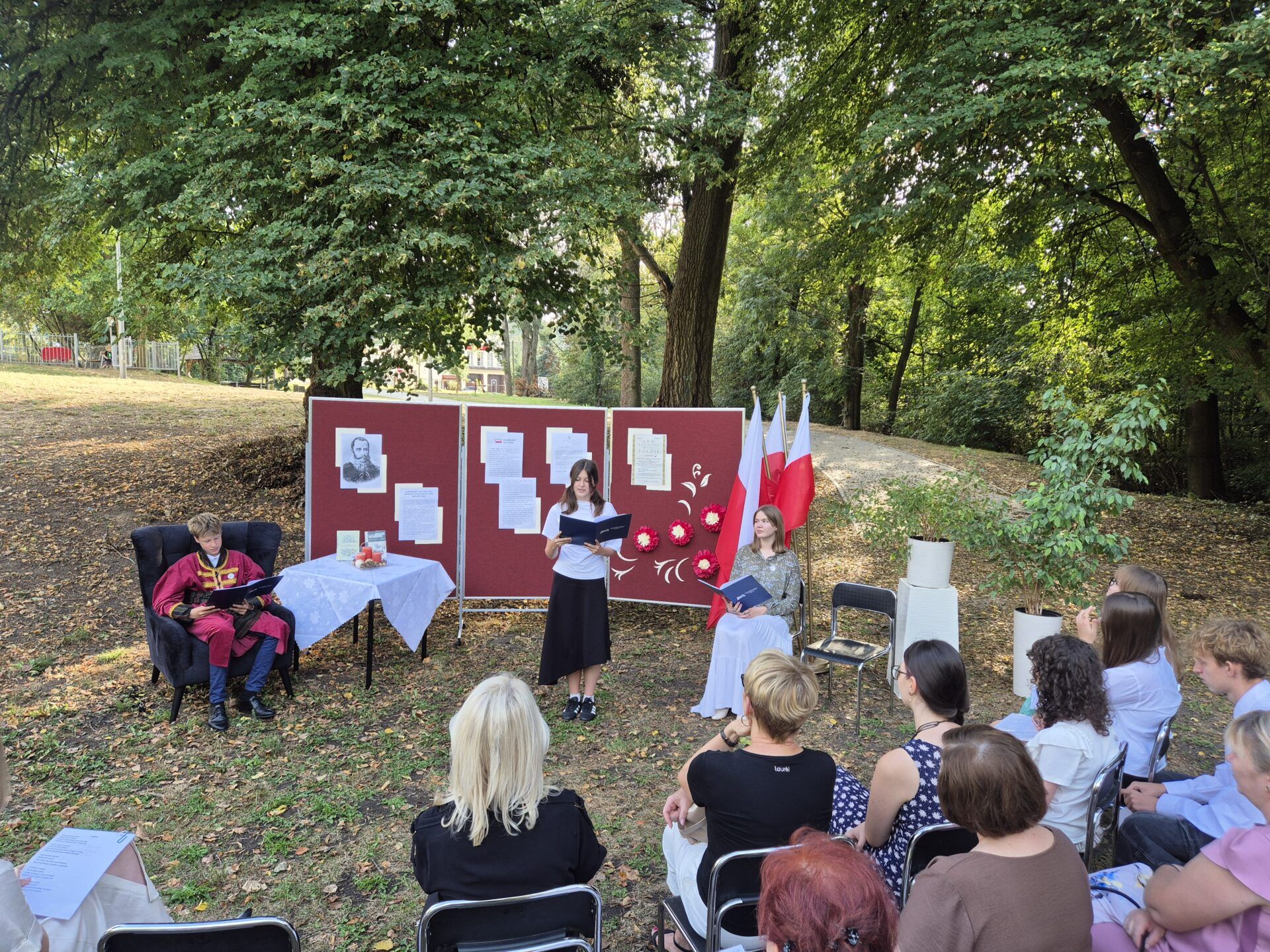 Uczestnicy Narodowego Czytania w plenerze pod lipą.