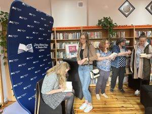 Cztery czytelniczki czekające na autograf agaty Kołakowskiej podczas spotkania autorskiego w bibliotece.