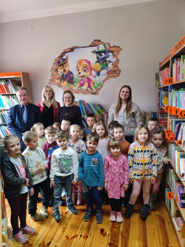 Zdjęcie grupowe: siedemnaścioro przedszkolaków wraz z opiekunem, Wójt Gminy, Dyrektor biblioteki oraz bibliotekarka.