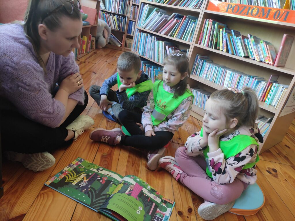 dwie dziewczynki i chłopiec z bibliotekarką na lekcji bibliotecznej
