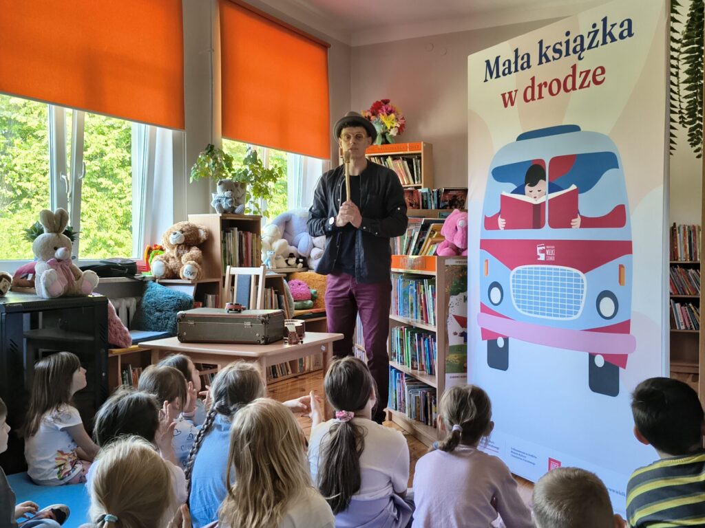 Piętnaścioro dzieci uczestniczących w warsztatach czytelniczych z animatorem Krystianem Truchalskim w GBP w Garbowie.