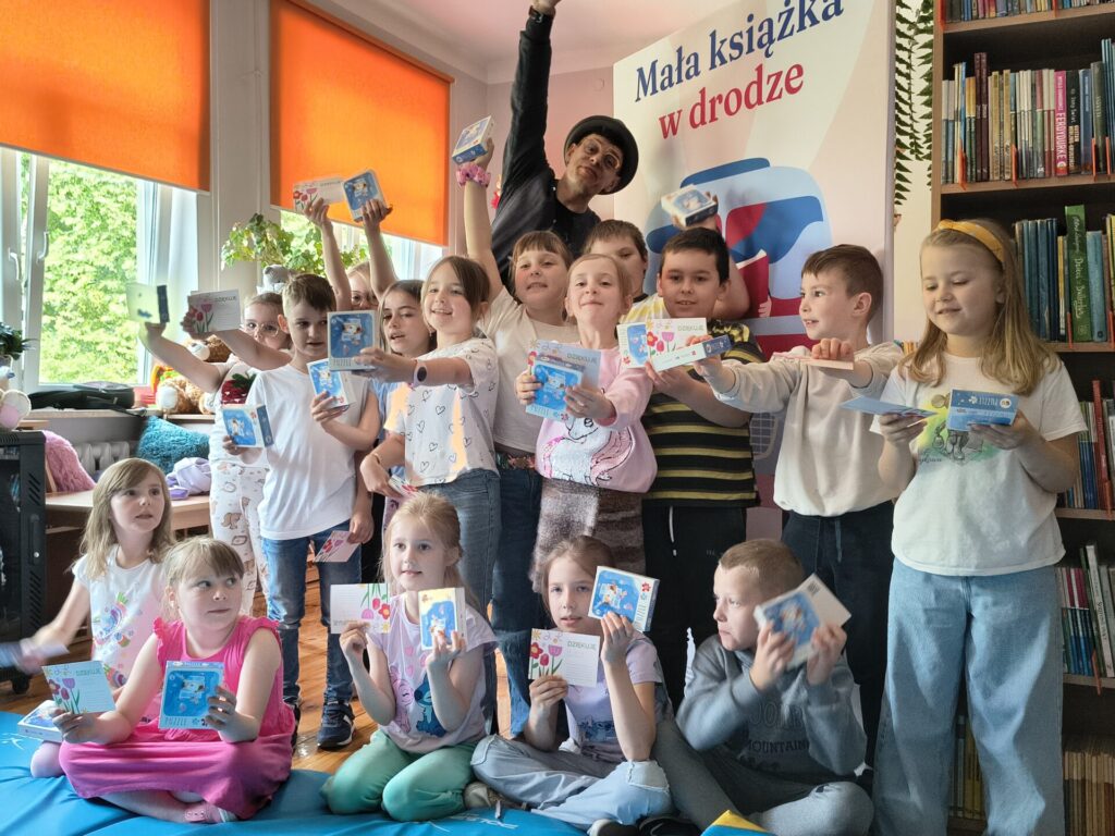 Piętnaścioro dzieci uczestniczących w warsztatach czytelniczych z animatorem Krystianem Truchalskim w GBP w Garbowie.