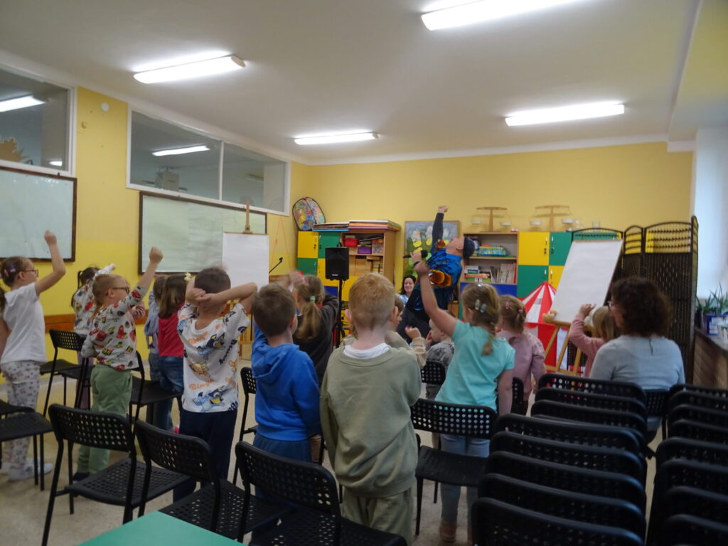 Grupa przedszkolaków w sali szkolnej uczestniczących w spotkaniu autorskim z Edytą i Robertem Zarębskimi.
