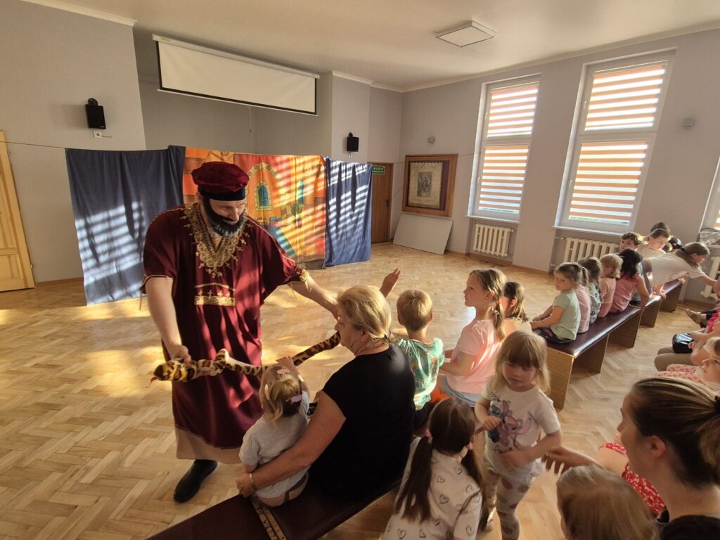 Grupa dzieci wraz z aktorami podczas przedstawienia teatralnego "Latający Kufer"