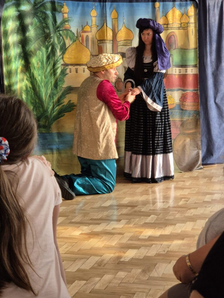 Dwójka aktorów z grupy teatralnej Krak-art na tle zamku, w przedstawieniu teatralnym "Latający kufer".