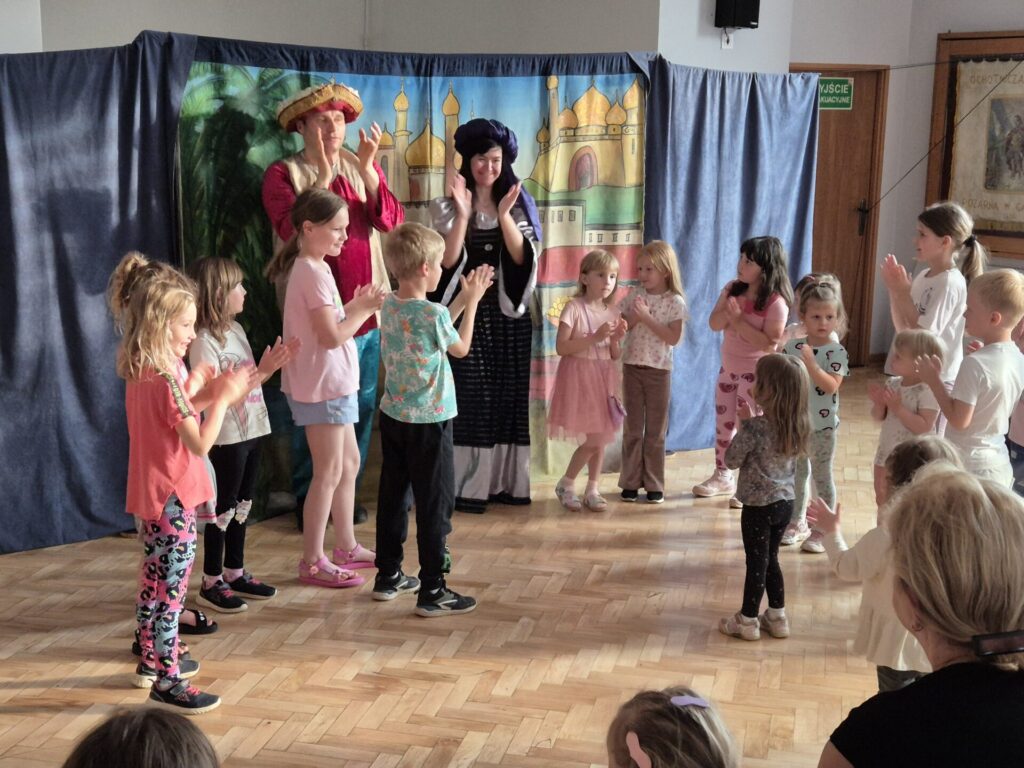 Grupa dzieci wraz z aktorami podczas przedstawienia teatralnego "Latający Kufer"