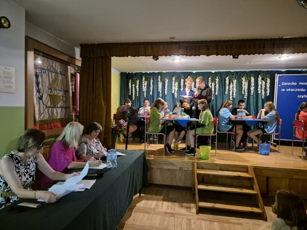 Cztery trzyosobowe zespoły uczniów Szkoły Podstawowej w Bogucinie oraz jury podczas Turnieju Wiedzy o Wandzie Chotomskiej.