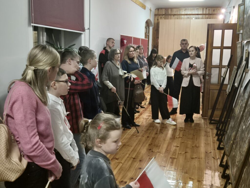 Uczestnicy biorący udział w obchodach Święta Niepodległości w bibliotece, oglądający wystawę malarstwa K. Zlot.