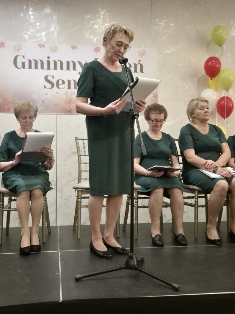 Seniorzy z Koła Rencistów i emerytów w zagrodach biorący udział w Narodowym Czytaniu podczas Gminnego Dnia Seniora