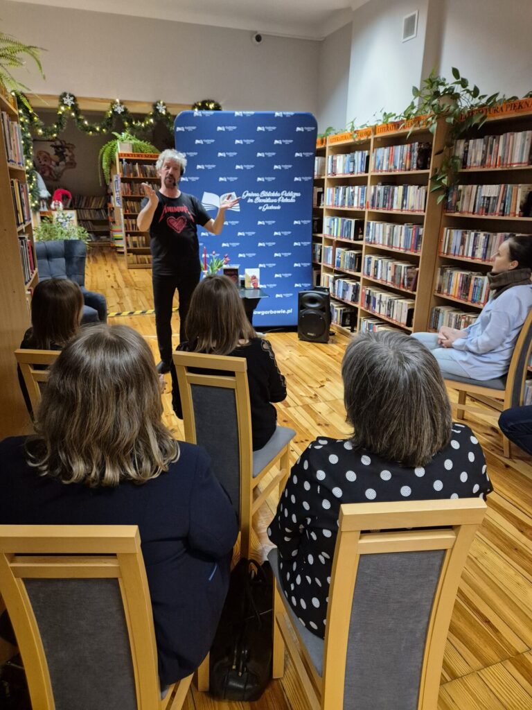Piotr Pilarski oraz uczestnicy spotkania autorskiego w bibliotece.