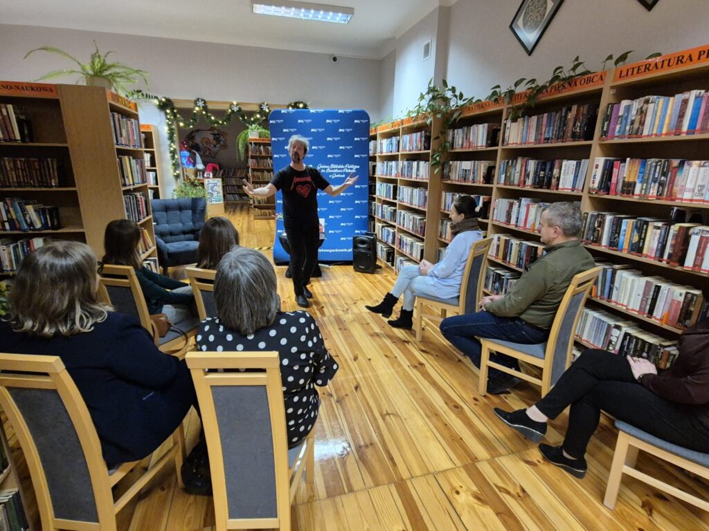 Piotr Pilarski oraz uczestnicy spotkania autorskiego w bibliotece.