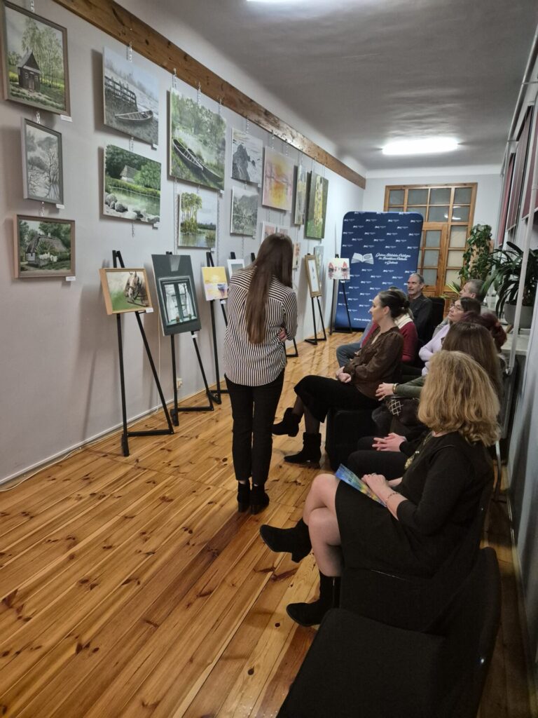 Kilkanaście osób na wernisażu malarstwa.