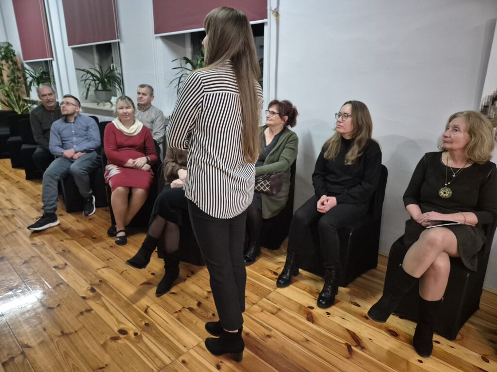 Kilka osób na wernisażu malarstwa.