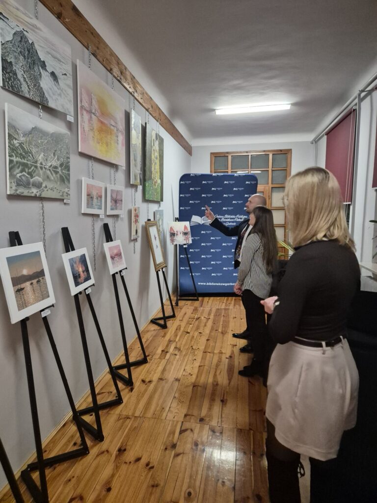 Trzy osoby oglądające obrazy.