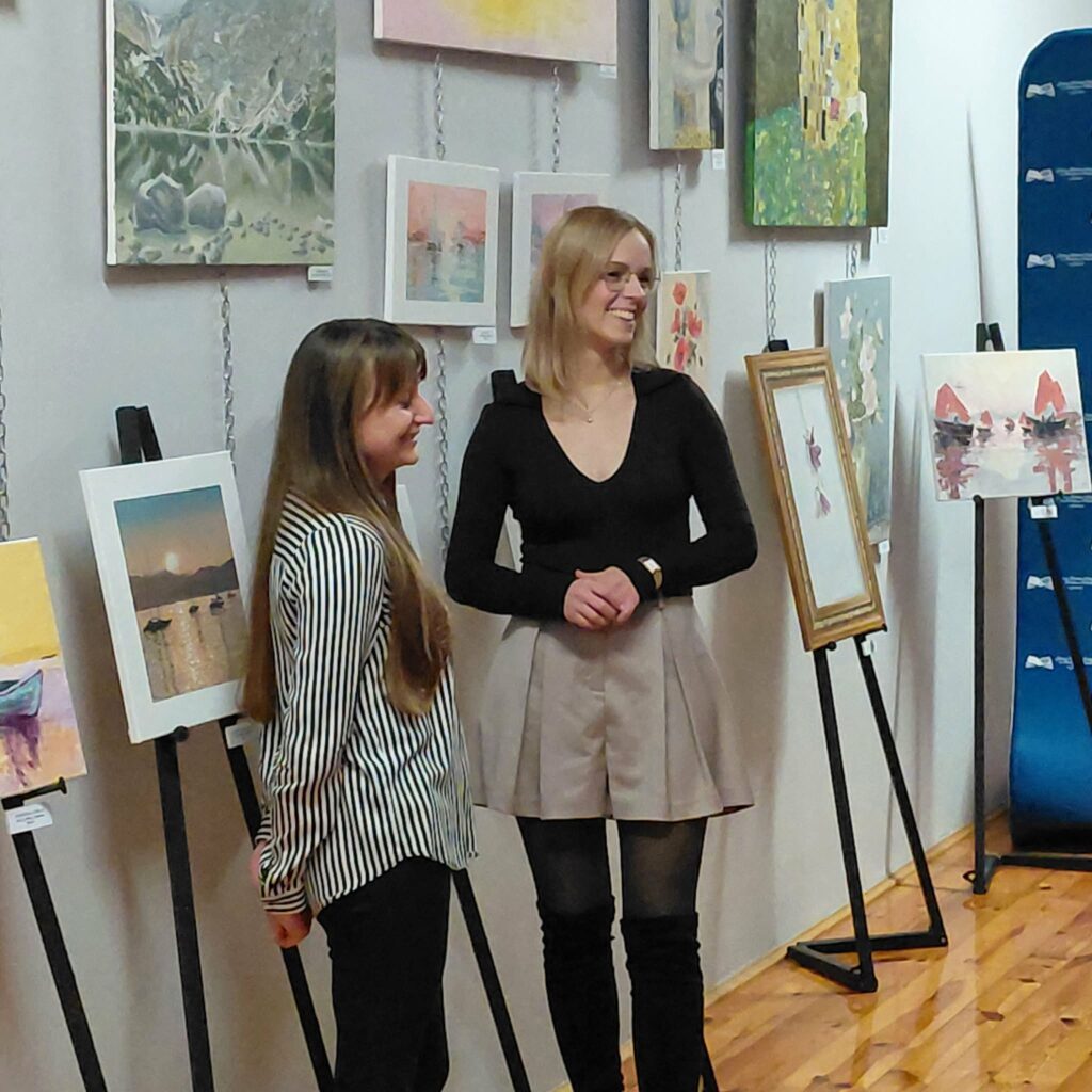 Dwie kobiety na tle obrazów.
