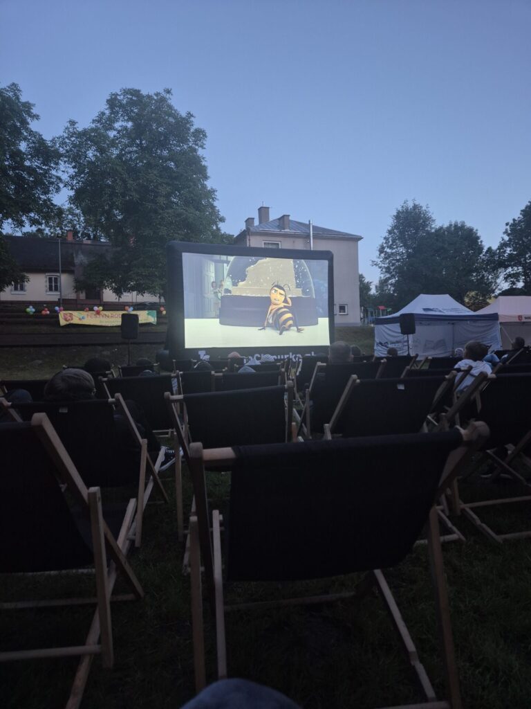Widzowie leżący na leżaczkach podczas wyświetlania filmu w plenerze.
