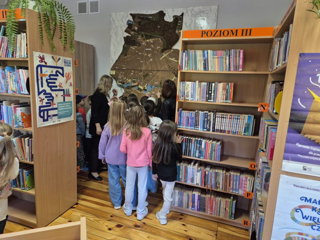 Dzieci ze Szkoły Podstawowej w Garbowie oglądające makietę Gminy garbów znajdującą się w bibliotece